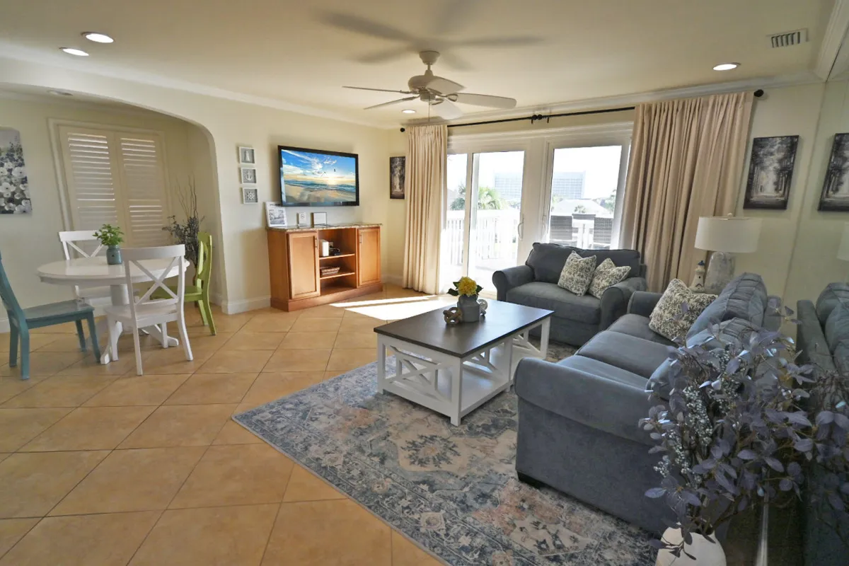 A comfortable, casual dining area featuring a dining table set near a sofa and TV, with curtains framing the background. The setup reflects a seamless flow between dining and living space, perfect for family meals or game nights.