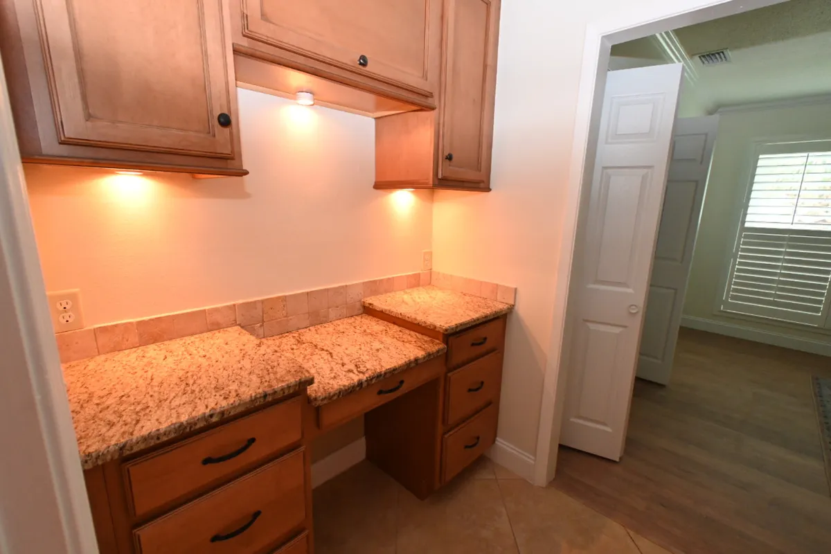 A functional and inviting kitchen scene with a granite countertop, wooden cabinetry, and under-cabinet lighting. The space is organized and ready for meal preparations or sharing recipes with loved ones.